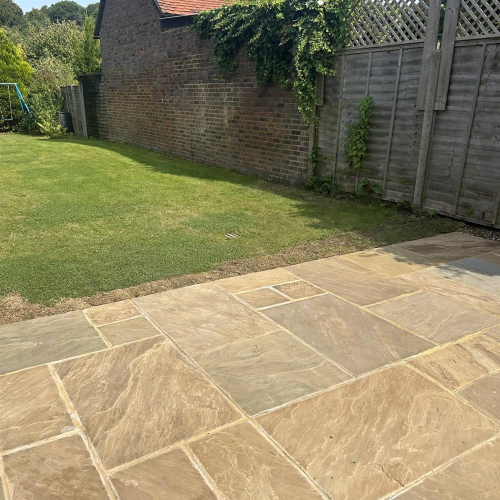 Sunset buff sandstone paving patio pack in a sunny garden with a lawn